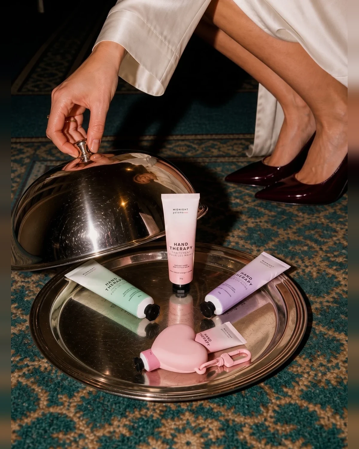 Midnight Paloma Mini Hand Therapy in French Rose + Vanilla, shown with other Hand Therapy minis and the pink heart holder on a silver tray